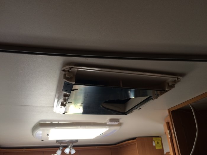 Installation av aircondition i taket på en husvagn, med synliga hålkanter och kablar.