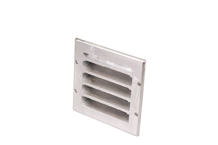 Grå fyrkantig ventilationsspis med flera horisontella lameller, avsedd att putsas in i en vägg.