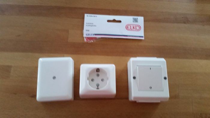 Inköpta elinstallationsprodukter: väggströmbrytare, eluttag och kopplingsdosa på träyta.