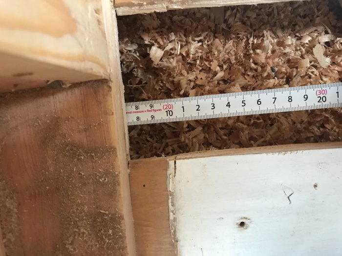 Öppnat golv med synlig regel, mätband och spån, undersökning inför byte av undergolv och ventilation.