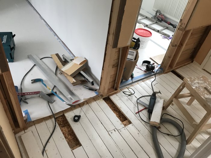 Renoveringsarbete med verktyg och upprivet golv i en hall under konstruktion.