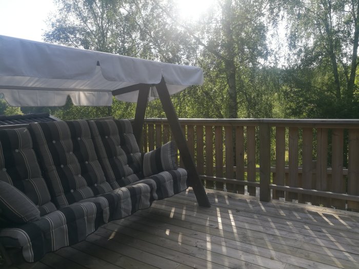 Altan med en hammock under ett solsegel omgiven av grönskande trädtoppar.