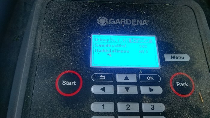 Display på robotgräsklippare som visar signalvärden, med texten "Signalvärde: 100" och "I laddstationen: NEJ".