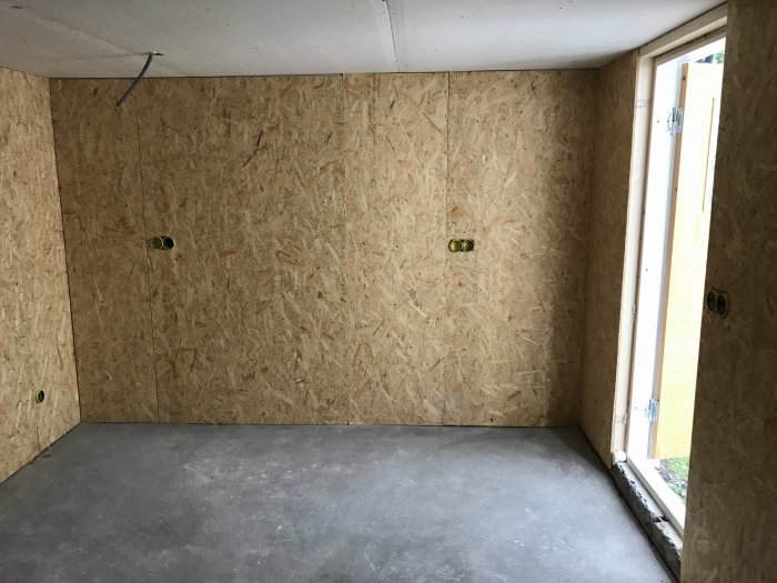 Rum under renovering med OSB-skivor på väggarna, isolering syns inte, väntar på gipsning.