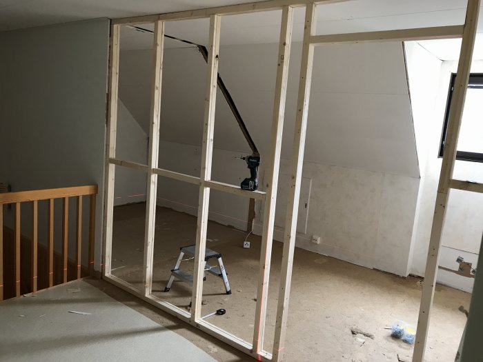 Nybyggd träregelvägg i ett hus under renovering med verktyg och material synligt.