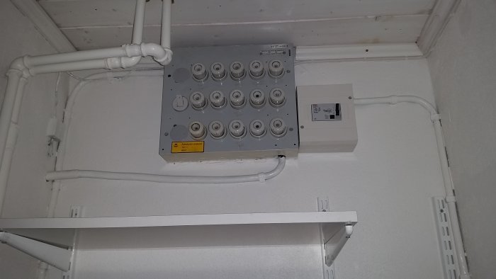 Elcentral med säkringar på vägg, kablar anslutna ovanifrån och till vänster, jordfelsbrytare till höger.