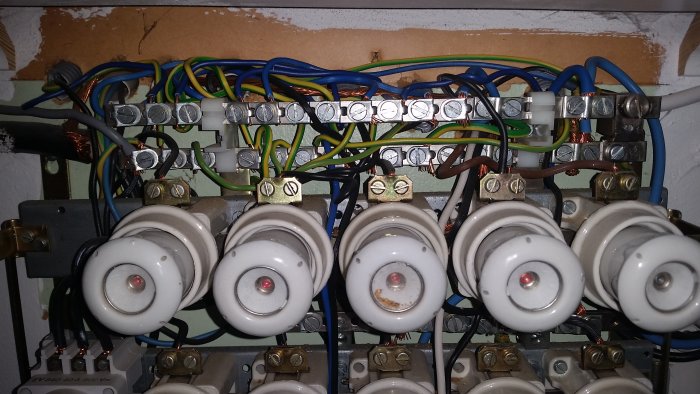 Närbild av elektriska säkringar och anslutna kablar i en säkringslåda.