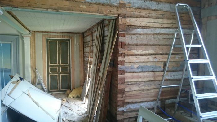 Renoveringsrum med borttagen väggpanel, synliga träbjälkar och en stege.