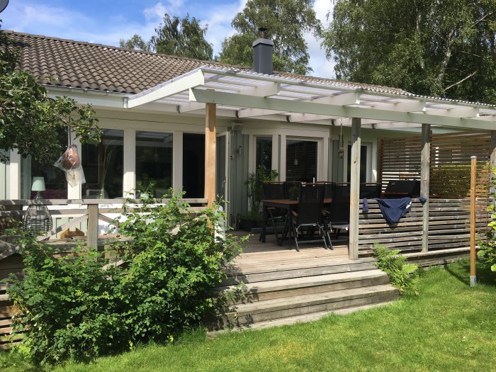 Trädäck med tak och uteplats vid ett hus, perfekt plats för en grill enligt Helene.