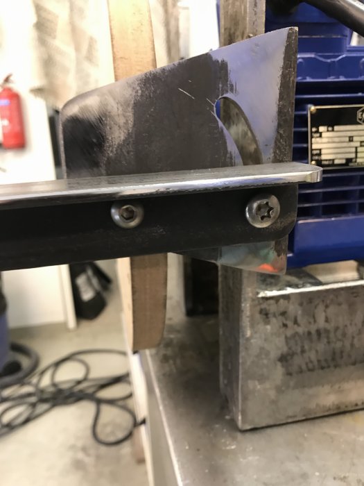 Närbild på prototyp av tiltbart bord i MDF med synlig spalt mellan bord och tallrik i verkstadslokal.