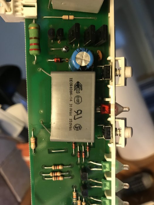 Kretskort från en Electrolux köksfläkt med reläer, kondensatorer och andra elektroniska komponenter.