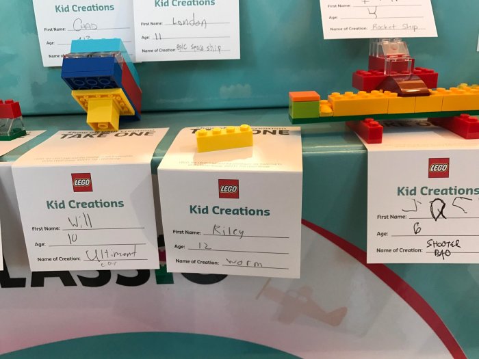 LEGO-kreationer av barn presenterade på vita tavlor med namn och ålder, bland annat en rymdfarkost och en bil.