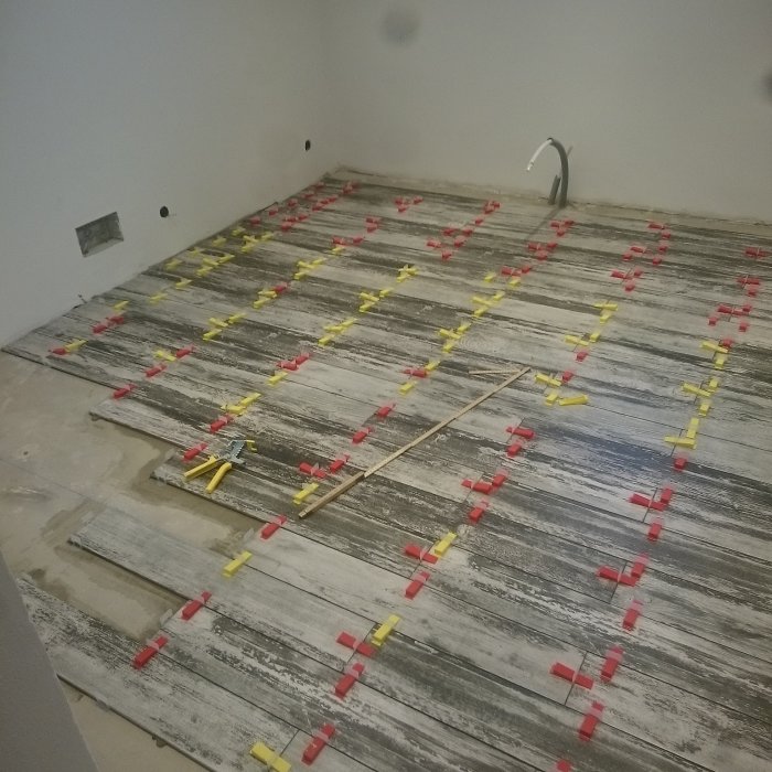 Utläggning av plattor i klädkammare med nivelleringskilar och avståndskors.