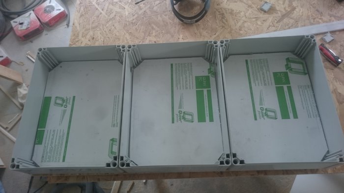 Elektriska installationslådor på golv med verktyg och kablar i bakgrunden, redo för inkoppling.