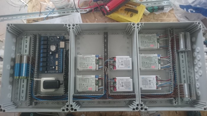 Ett öppet elskåp med monterade elektriska styrdon och organiserad kabeldragning i en källare under installation.