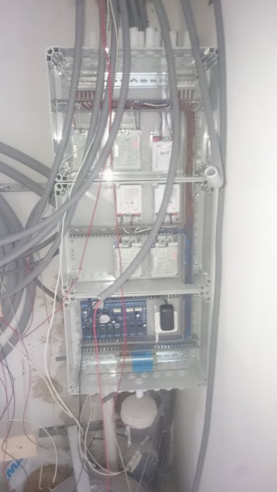 Elcentral med öppen dörr visar installation av säkringar, kablar och styrdon i en källare.