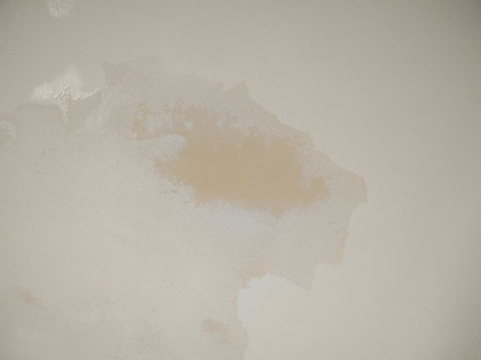 Tak med delvis borttagen limfärg som visar oskrapad, skrapad och skrubbad yta samt grundad underyta.