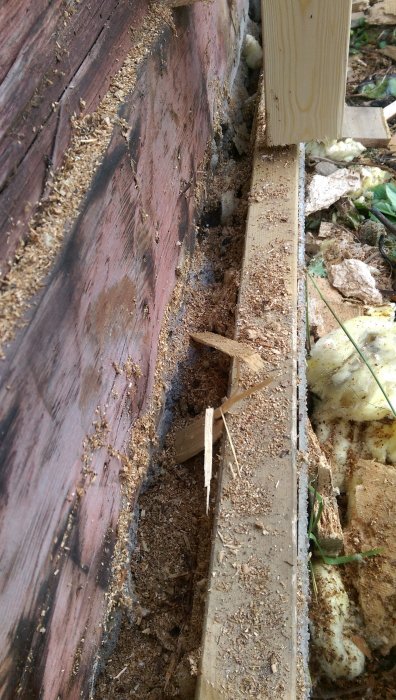 Detaljerad bild av en springa nederst vid en isolerad vägg med synliga krypgrundsstenar.