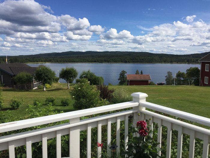 Utsikt över Styrsjön från vit veranda med trädgård och röda hus i förgrunden.