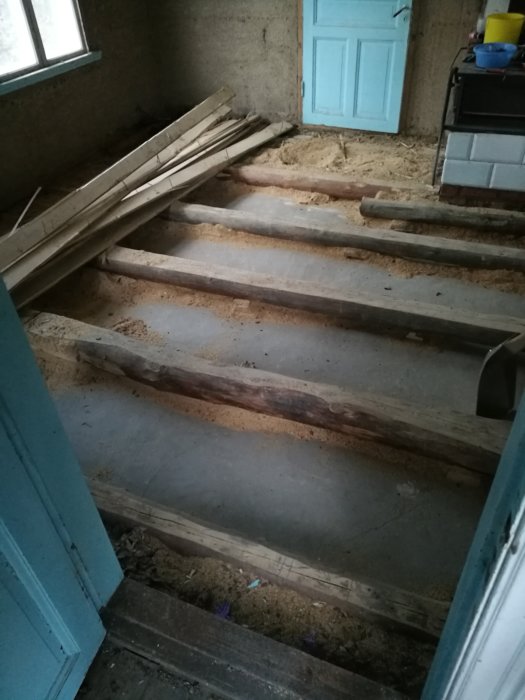 Upprivet gammalt trägolv med synliga bjälkar och betongkaka i krypgrund i hus från 1900-talets början.