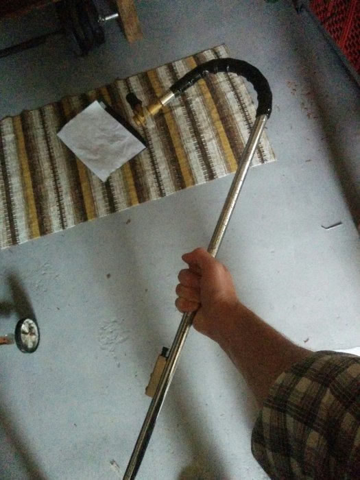 Hand håller en improviserad slägga gjord av en brännare och några tänger för att smida en krok.