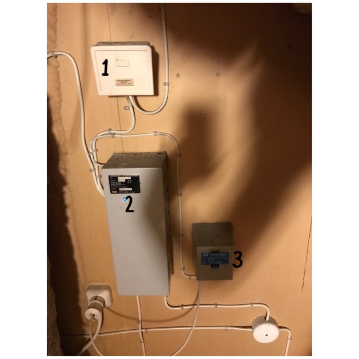 Vindutrymmet med elektriska dosor och avklippta kablar fastskruvade på en brun vägg, några kablar ligger löst.