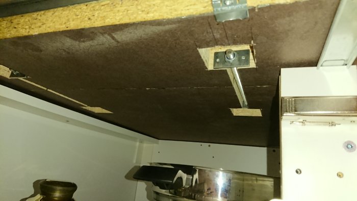 Undersida av en sammansatt träskiva med hemmagjorda metalldelar för skarvförstärkning.