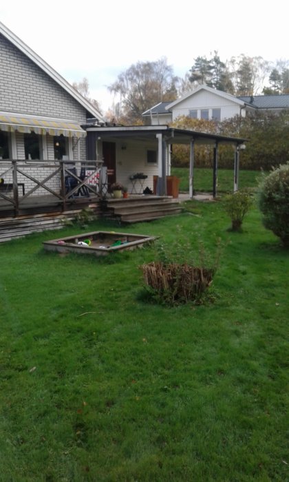 Altan under renovering framför ett hus, med verktyg på marken och omgiven av en gräsmatta.