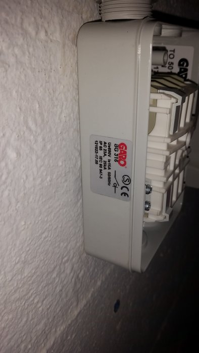 Elektrisk dosa på vägg med ogenomtränglig hårdplast över gängat hål för kabelgenomföring.