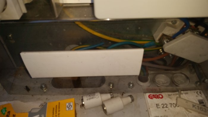 Elektrisk central med inkommande kabel till vänster och kablar som går till hus och garage till höger.