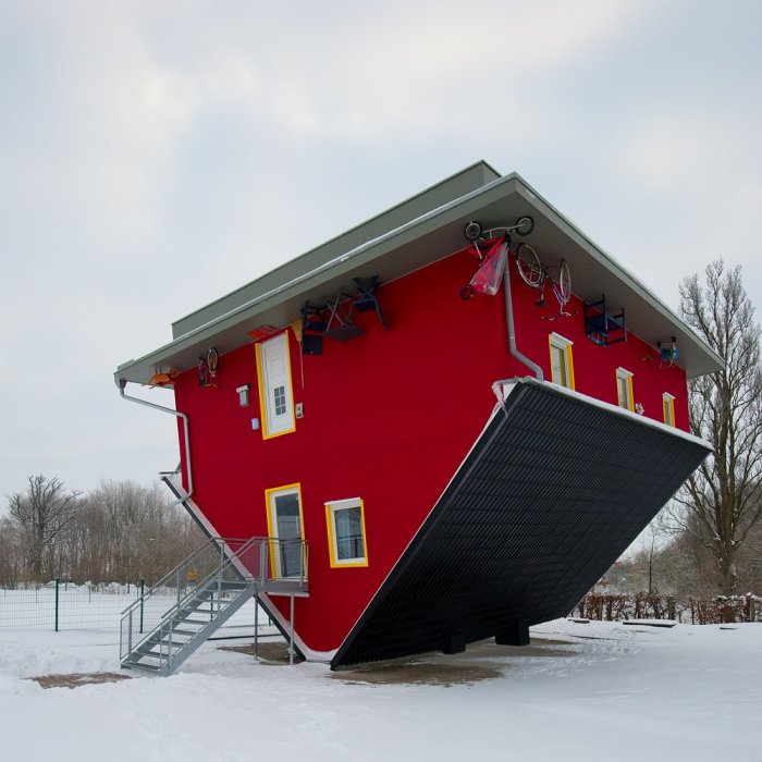 Upside-down house with red exterior and yellow trim, suggesting need for rotation.