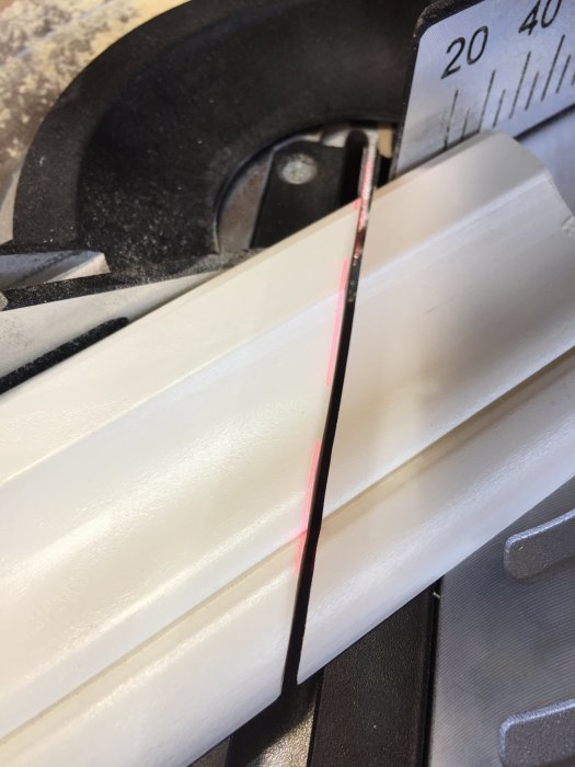 Färdigmålat allmoge dörrfoder placerat i gersåg med laserstråle för precisionssågning.