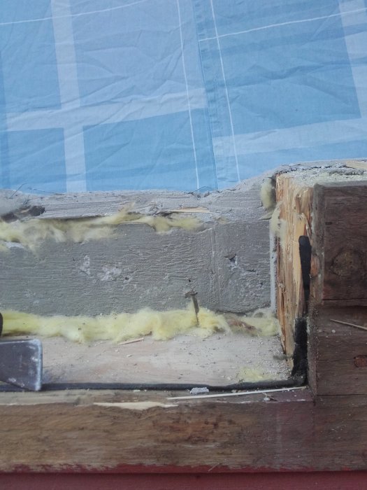 Gamla reparationer på en träkonstruktion med isoleringsskum och blå presenning.