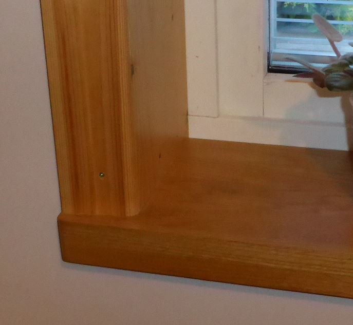 Eget snickeriarbete med en noggrant utformad träfoder runt ett fönster.