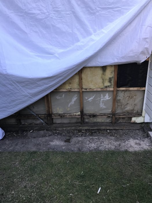 Husgrund med borttagen panel som visar isolering och syllar direkt på marken.