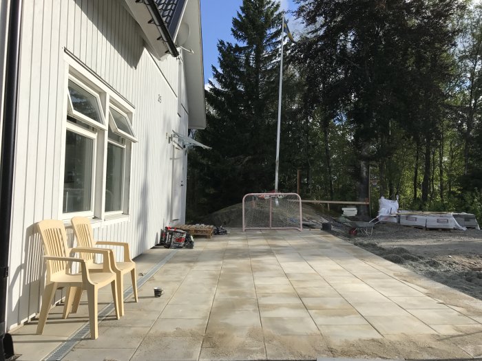Halvfärdig läggning av stenplattor för uteplats, byggmaterial och hockeymål syns också.