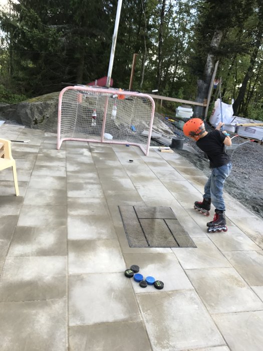 Barn på inlines åker på nylagda plattor vid ett pågående byggprojekt med grushög och byggmaterial i bakgrunden.