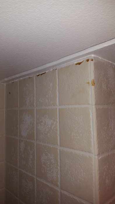 Kakel med ljusbruna fläckar högst upp och vitaktig beläggning på plattorna.