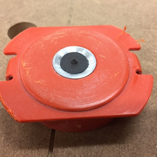 Orange hole saw attachment with pilot drill bit for creating precise holes in wood panels.