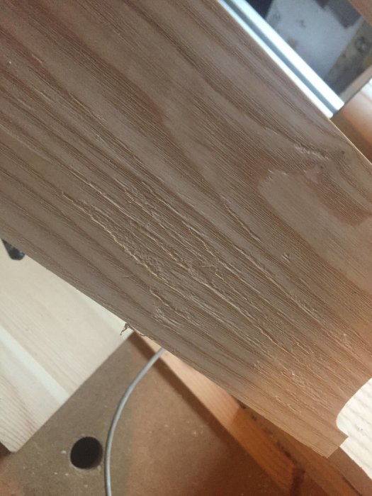 Askskiva med längsgående ådring och urslag efter hyvling med bevel up smoother.