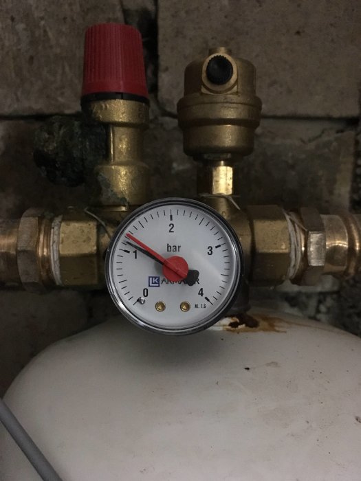 Tryckmätare på 1,1 bar monterad på VVS-installation med röda och guldiga ventiler.