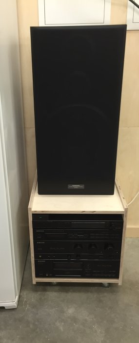 Audio systems temporarily set up on a wooden platform in a garage.