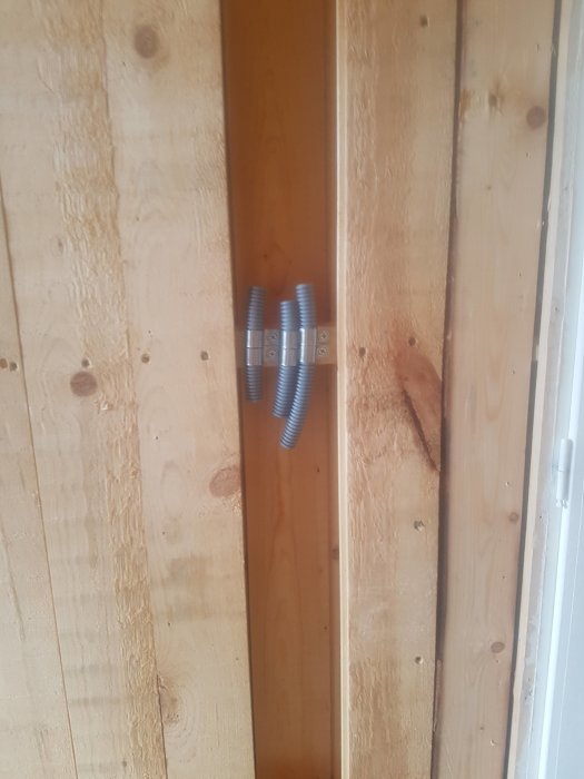 Elrör dragna bakom en regel i ett träväggskonstruktion med råspontklädsel.
