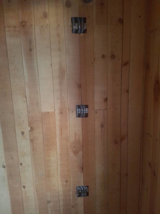 Trävägg med tre synliga eluttag installerade på råsponten utan föregående urtag för reglar.