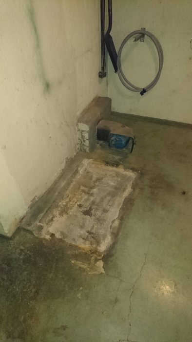 Tomt hörn i ett pannrum med betonggolv och spår efter borttagen oljepanna, betongfundament och väggar som behöver renovering.