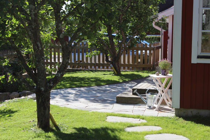 Nygräddat gräs framför husentré med granitstolpar, sandstensgång och stentrapp.