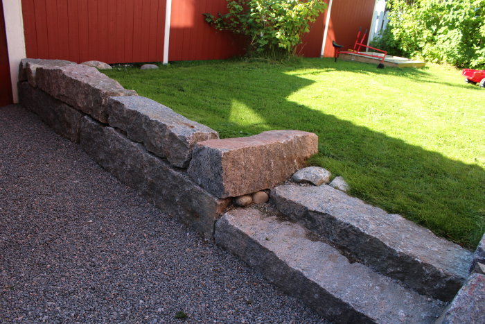 Återanvända granitstolpar och sandstenstrappor utgör entrén till huset med nyvuxet gräs och grusgång.