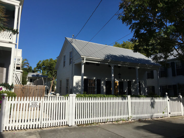 Vitt staket framför klassiska hus i Key West med skylt som säger "Do Not Block Driveway