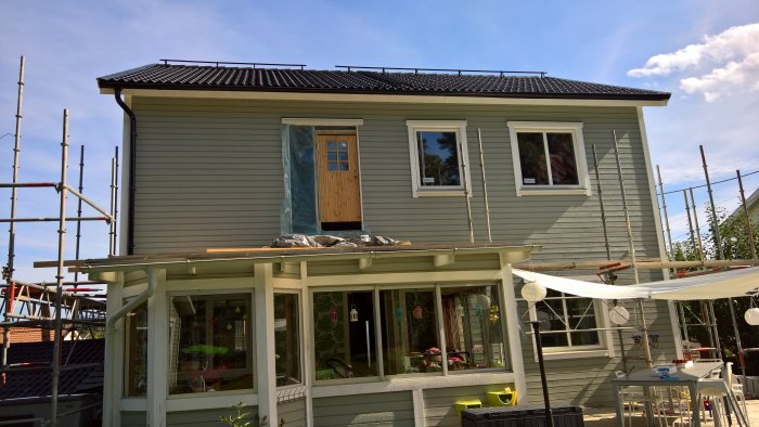 Hus under renovering med delvis nedmonterad byggställning och takterrass.