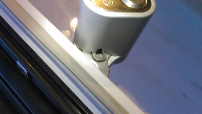 Låscylinder med låsbricka och cylinderskruv monterade i dörrhandtag.